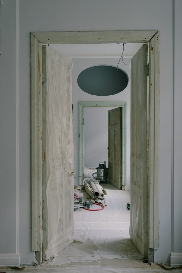 Interior view of an apartment under renovation with open doors and tools.